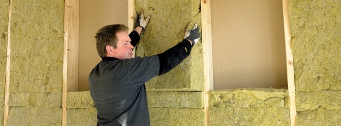 Man fitting insulation slab in a loft.