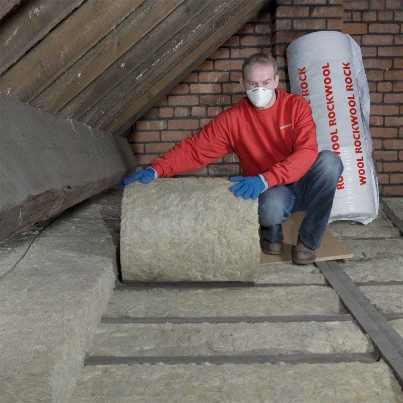 Man fitting ROCKWOOL mineral wool insulation in a loft.