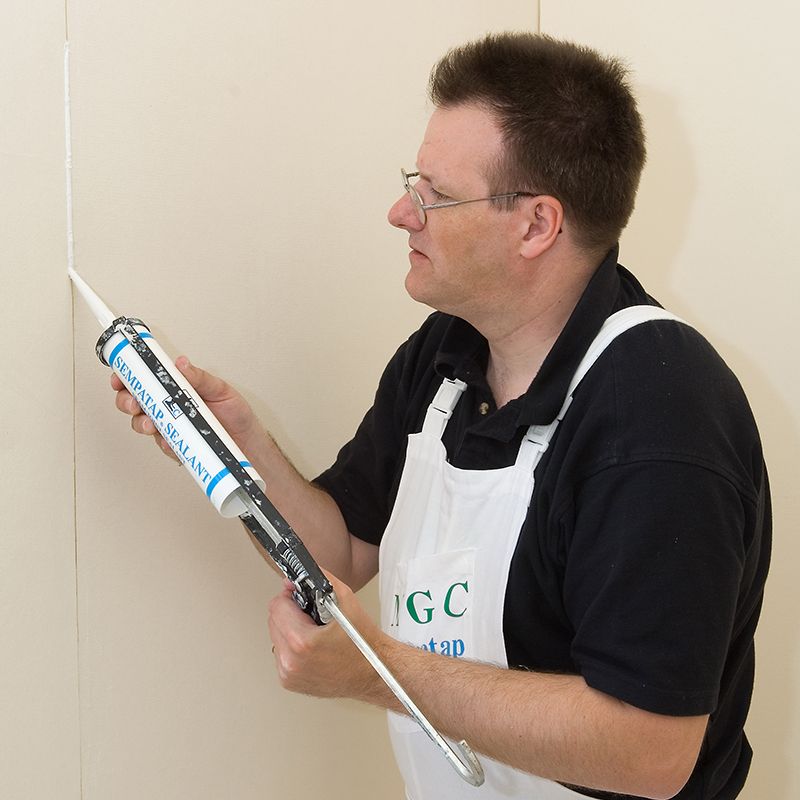 Person applying adhesive to insulated plasterboard