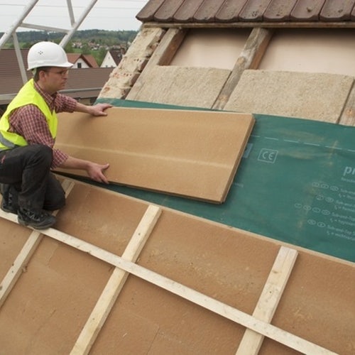 A tradesman fitting insulation board on a roof
