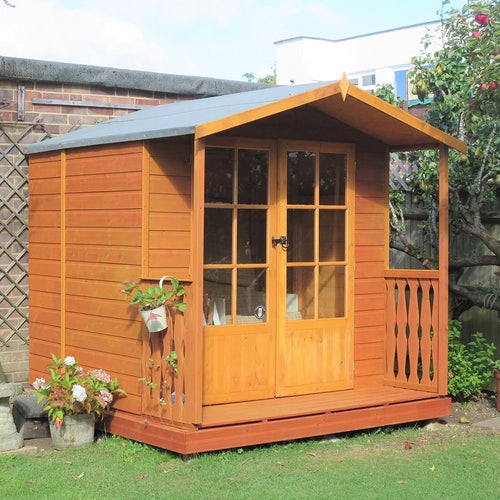 A summer house with planters in a garden corner.