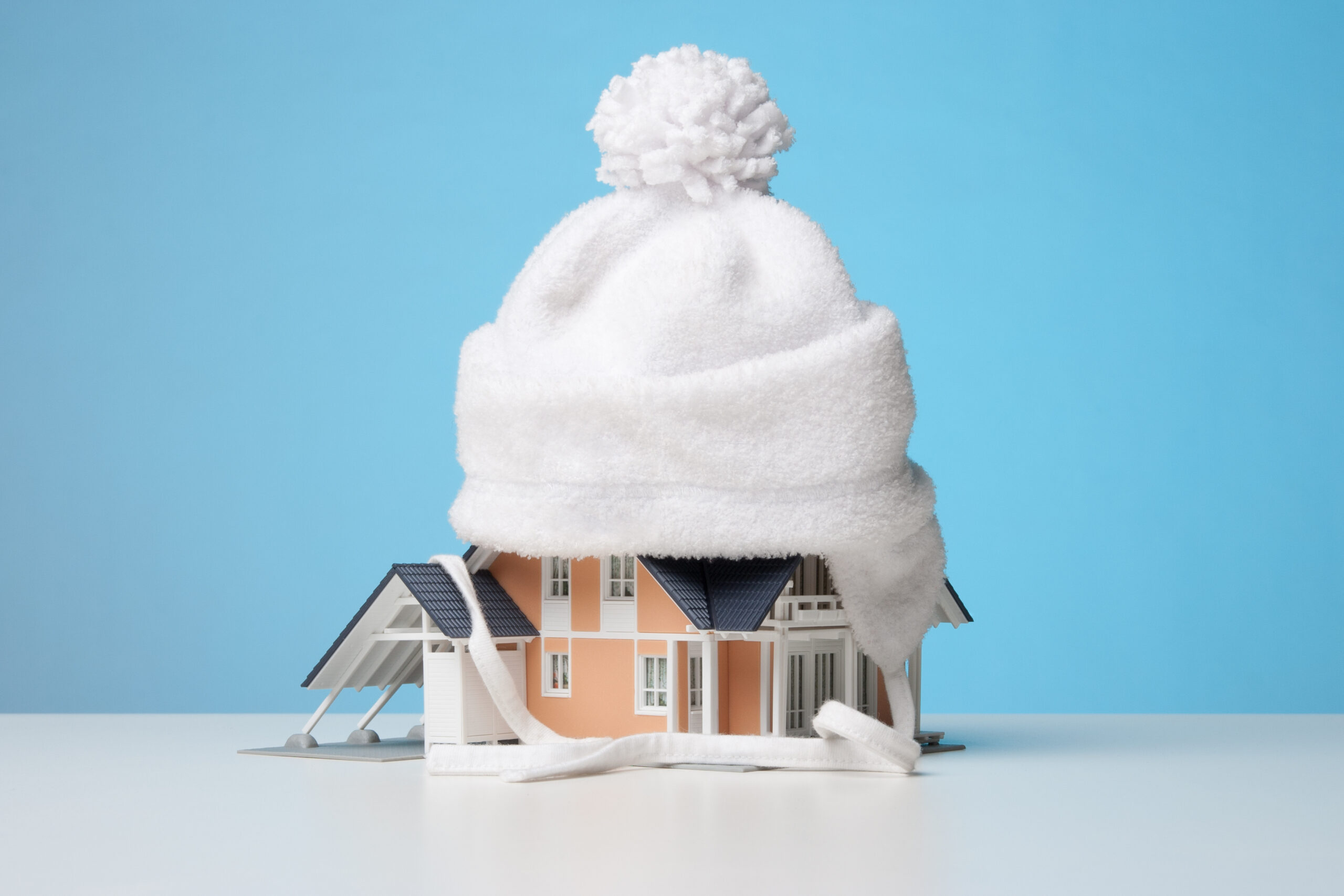 Warm house stock image of a small house with a bobble hat placed on the roof