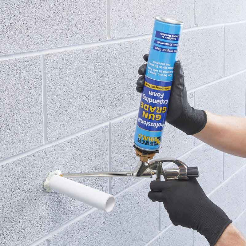 Person sealing a pipe in a wall.