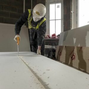 Tradesperson wearing PPE cutting an insulation board.
